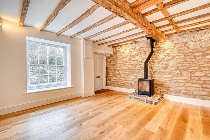 A beamed front room with a freshly skimmed ceiling and exposed stone wall