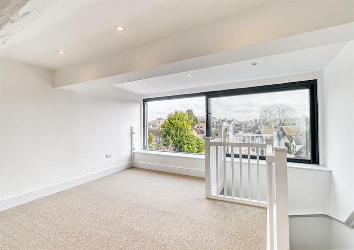 A master bedroom with a large sliding feature window, plastered and painted