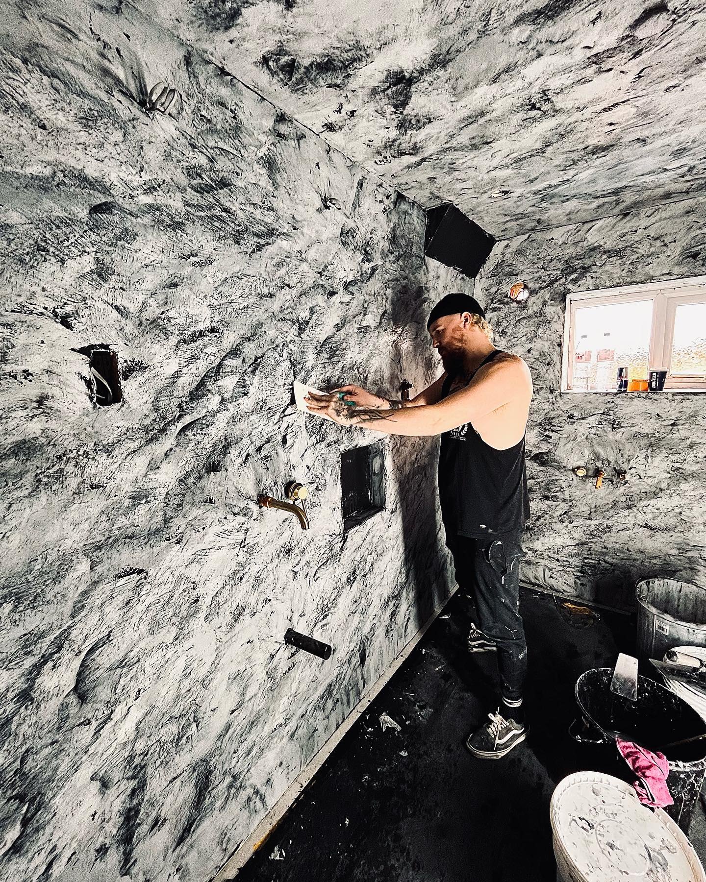 Oscar trowelling a two-tone tadelakt finish onto a bathroom wall