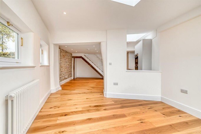 A renovated room with oak floors, plastered walls and a view through to the next room