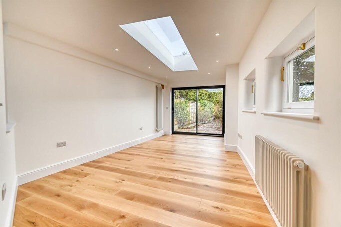 The finished rooflight room with oak floors, white walls and sliding doors to the garden