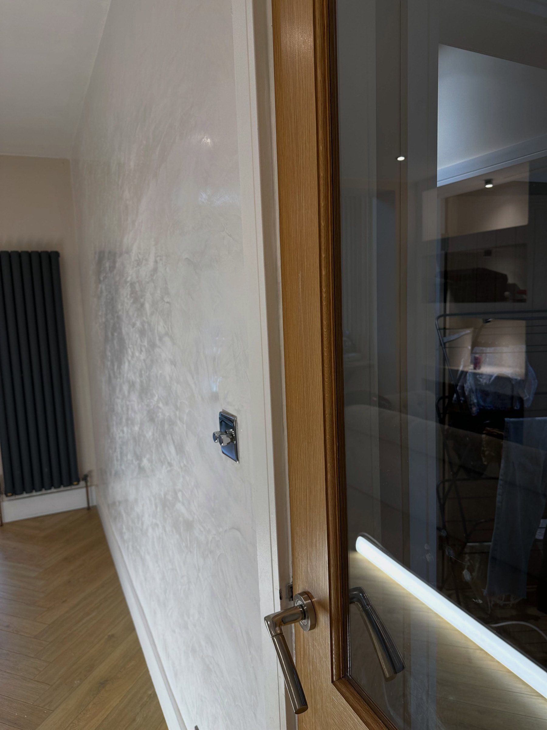 Close-up of a polished off-white Venetian plaster wall catching the light